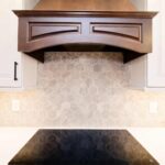 Kitchen remodel with white cabinets, custom wood range hood and hexagon tile backsplash